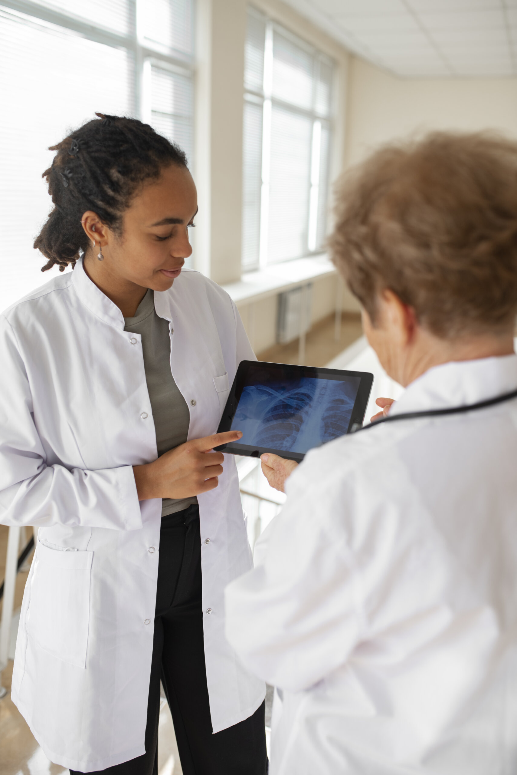 Two colleagues in white coats with one showing an image on a tablet.